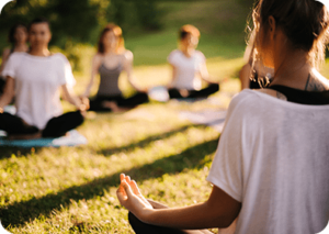 women sat in a group meditating